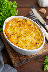 Homemade Shepherd's Pie in the casserole dish on a dark wooden background. Traditional British dish...