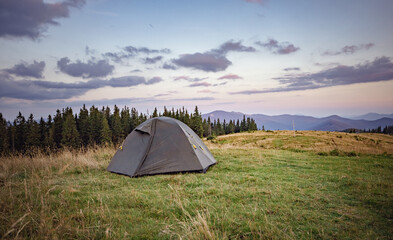 mountain holiday concept. tent on top of the mountain. incredible landscape in the light of the setting sun © Nazar