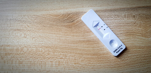 Covid antigen test kit on wooden table with copy space for people testing infected with virus by by...