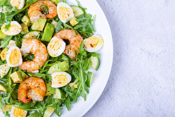 Salad with shrimp, avocado, cucumber, quail eggs and arugula. Mediterranean traditional cuisine. Close-up.