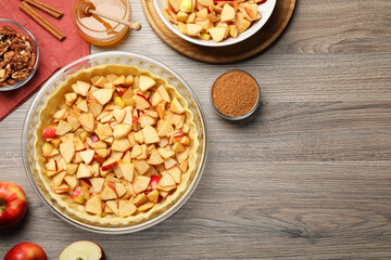 Flat lay composition with raw dough and ingredients for apple pie on wooden table