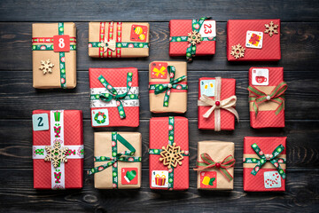 Handmade wrapped red, green gift boxes decorated with ribbons, snowflakes and numbers, Christmas decorations and decor on table Xmas advent calendar concept Top view Flat lay Holiday card