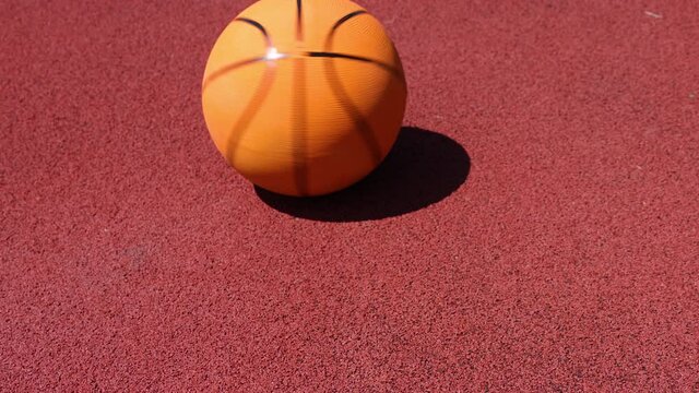 Basketball ball spinning on red outdoors court