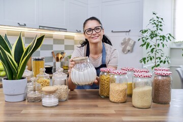 Food, grocery storage, smiling woman looking at the camera in the kitchen.