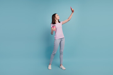 Full size photo of young cheerful girl drink coffee make selfie smartphone isolated turquoise color background