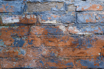 Fototapeta premium Grunge texture brick wall background. Close-up of old cracked blue red paint on brickwork, exterior of rough wall outdoors