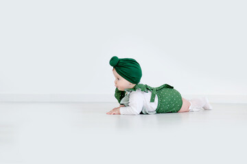 Little cute baby girl posing. A fashionable baby is photographed for advertising in green clothes