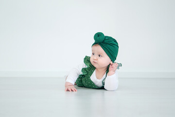Little cute baby girl posing. A fashionable baby is photographed for advertising in green clothes