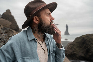 Man feeling happiness while spending his weekend at the Iceland beach and smoking