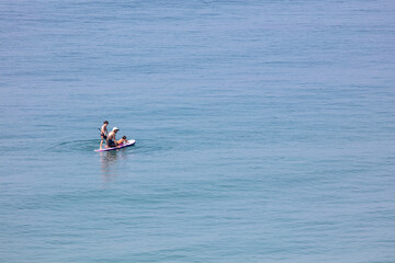 Fototapeta na wymiar Father and His Children on a Paddle Board Exploring the Coast without Life Jackets