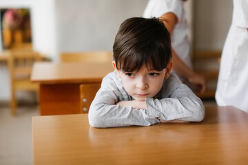 Fototapeta na wymiar Lonely sad child boy at school at a desk. Children's emotions, bullying at school.