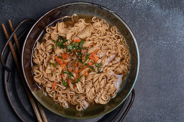 Instant noodles in gray Japanese ceramic lining with black tray, top view.
