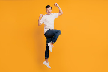 Fototapeta na wymiar Portrait of cheerful crazy excited guy jump celebrate victory on yellow background