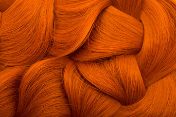 Red-haired Beautifully laid braid carroty curls.Female long red hair close-up as a background. Hair care shampoo and balsam for colored hair. Hairdressing procedures. Copy space with space for text.