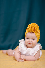 .A fashionable girl in a yellow hat poses..A baby in a white dress smiles