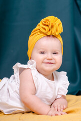 .A fashionable girl in a yellow hat poses..A baby in a white dress smiles