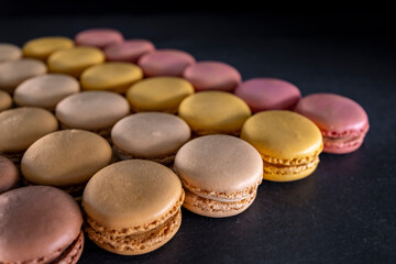 chocolate, coffee, vanilla, lemon and strawberry macaroons on black background