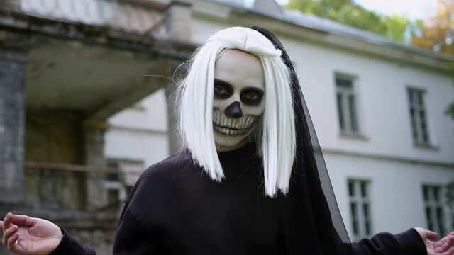 Close up portrair of womans face with skull makeup. Halloween costume party. The bride blows a kiss.