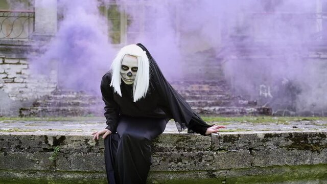 Dead bride sitting in the old house in a blue smoke. Halloween party.