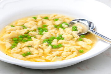 chicken bouillon with homemade dumplings and green peas