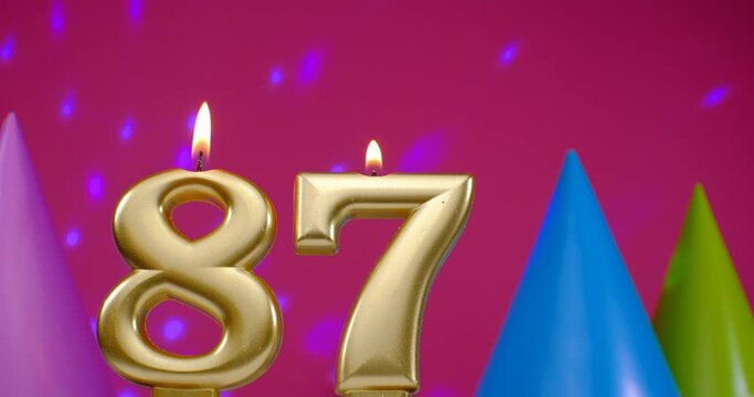 Burning birthday cake candle number 87. Happy Birthday background anniversary celebration concept. Birthday hat in the background