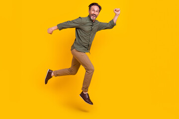 Full length body size view of attractive cheery lucky man jumping going isolated over vivid yellow...