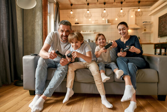 Overjoyed family with kids play video games at home
