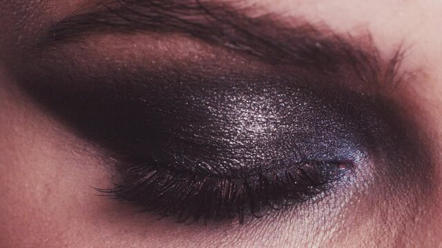 a girl with dark makeup opens her eyes