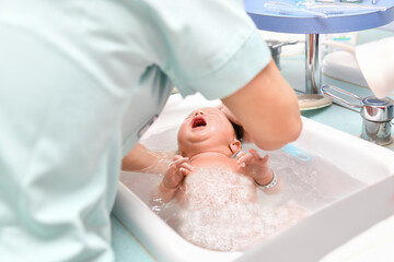 Obraz na płótnie Canvas A nurse gives the first bath of a newborn boy
