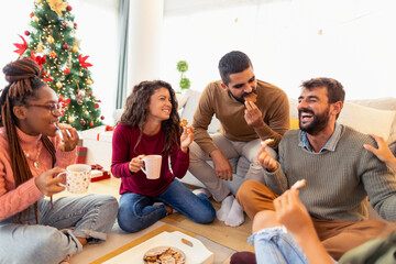 Friends eating gingerbread cookies and drinking coffee while celebrating Christmas
