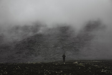 Fototapeta premium Lonely person standing at the black rocks and looking at the distance