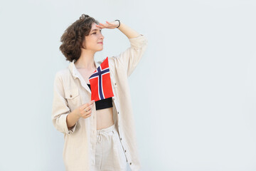 Young woman with the flag of Norway looks towards the place for text.