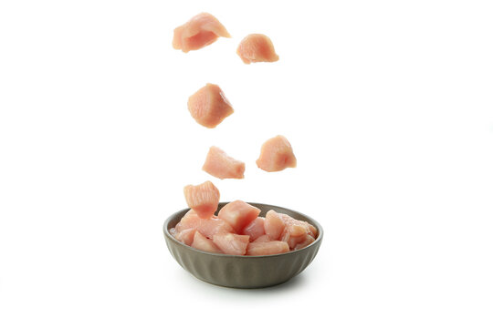 Raw chicken fillet slices falling in bowl, isolated on white background