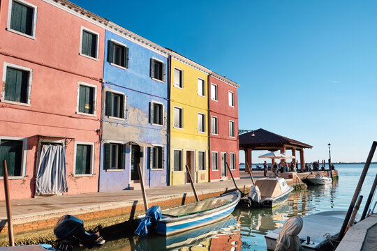 Burano island, Italy. Colorful houses alongside canal with boats. Historic italian architecture in historic village not far from Venice.