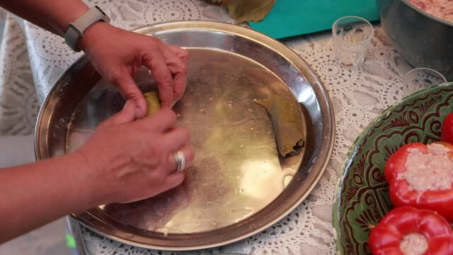 People cook dolma food.
Grape leaves stuffed with minced meat.