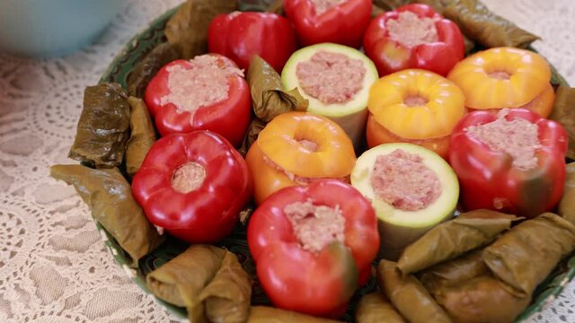 People hands are preparing food. Peppers, tomatoes, zucchini and grape leaves stuffed with minced meat.
