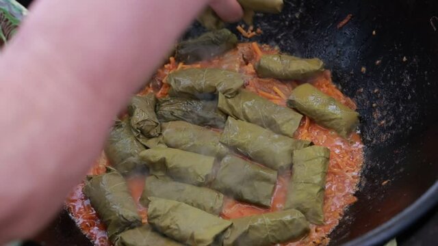 People cook dolma food.
Grape leaves stuffed with minced meat.