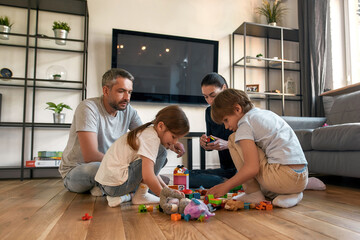 Fototapeta premium Caucasian parents with children play together with toys