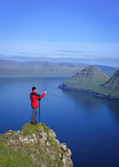 Fototapeta na wymiar Tourist photographs view of Funningur fjord and nearby mountains, Faroe Islands