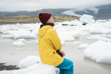 Female person sitting at ice and closed her eyes while spending time at the Scandinavia