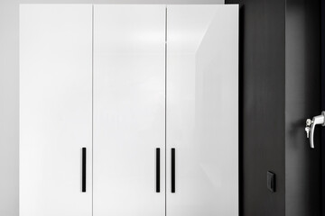 Large and high wardrobe in the bedroom with white fronts and black handles.