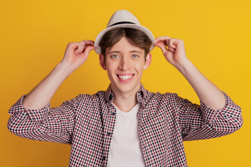 Photo of young cheerful man happy positive smile wear hat summer trip travel isolated on yellow color background