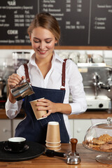The barista girl pours coffee into a disposable cup.