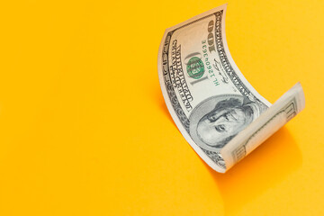 Single Hundred Dollar Bill Curled on yellow