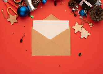Craft envelope with a blank sheet of paper and Christmas decoration on a red background