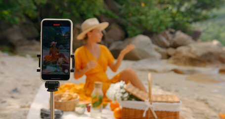 Girl in yellow dress and hat having live stream for video blog, shooting outdoor report on her phone