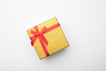 Gold gift box with a ribbon on a light background. Top view, flat lay. 