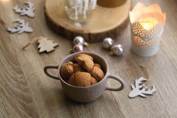 Bowl of cinnamon cookies, lit candles and various Christmas decorations on the table. Selective focus.