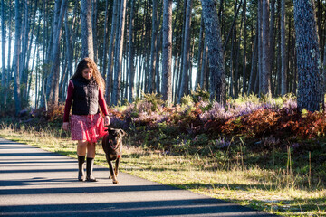 middle-aged woman walking in the forest with her dog