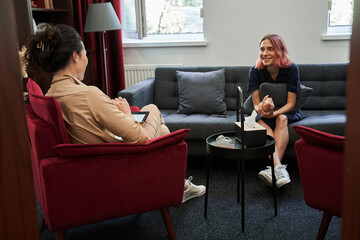 Girl with pink hair looking at therapist with happy expression after successful session - obrazy, fototapety, plakaty